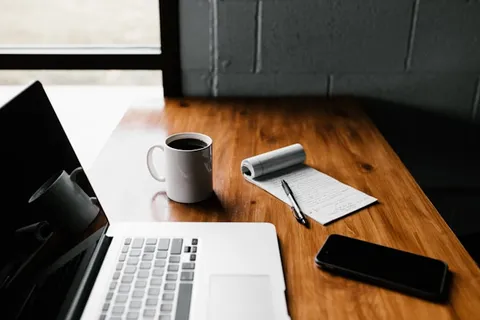 Un indépendant fait sa facturation sur son ordinateur portable autour d'un café